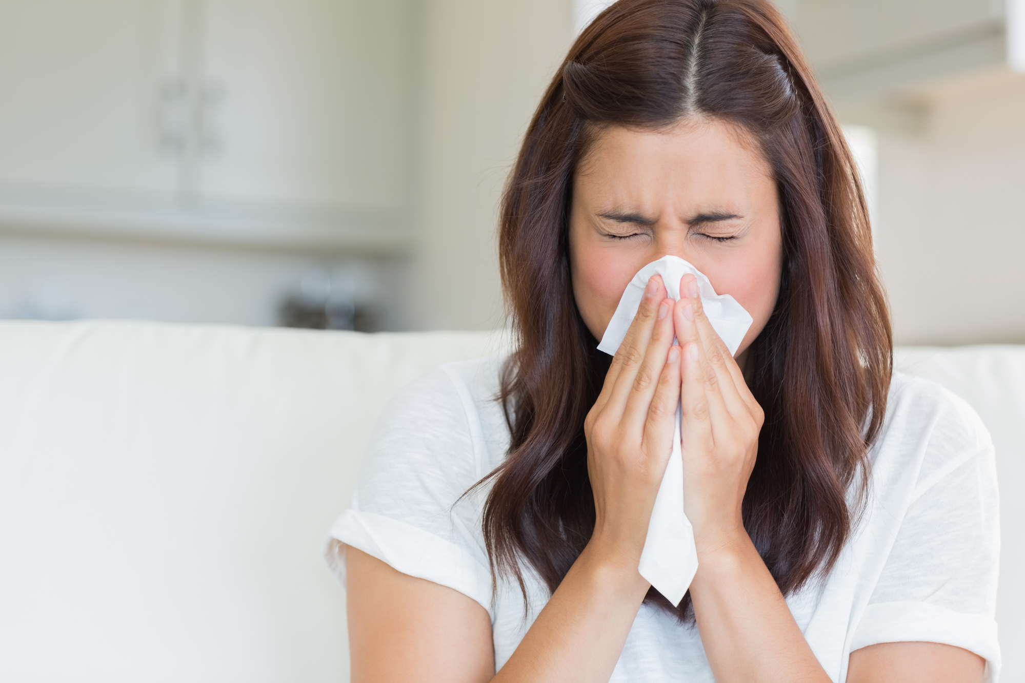 Woman sneezing in a tissue in the living room