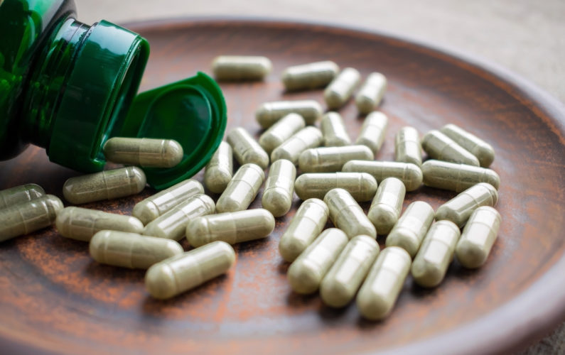 Green tea extract supplements and bottle on a clay brown plate