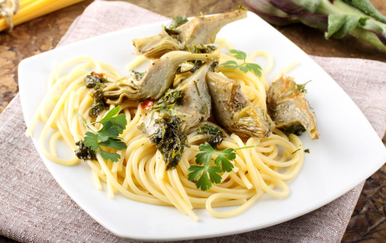Spaghetti with artichokes and parsley on complex background