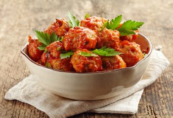 Meatballs with tomato sauce in a bowl on wooden table